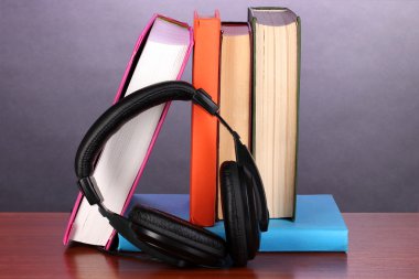 ahşap masa mor zemin üzerine kitaplar üzerinde kulaklık