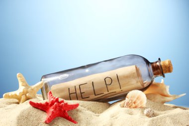 Glass bottle with note inside on sand, on blue background clipart