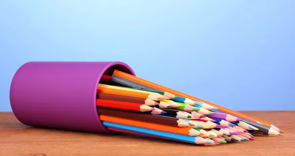 Lápices de color en vidrio sobre mesa de madera sobre fondo azul — Foto de Stock