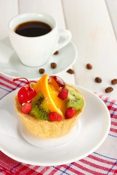 Süßer Kuchen mit Früchten auf Teller und Kaffee auf Holztisch — Stockfoto