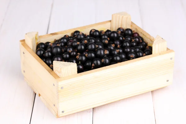 Black currant in crate on wooden background — Stock Photo, Image