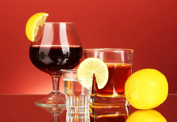 A variety of alcoholic drinks on red background — Stock Photo, Image