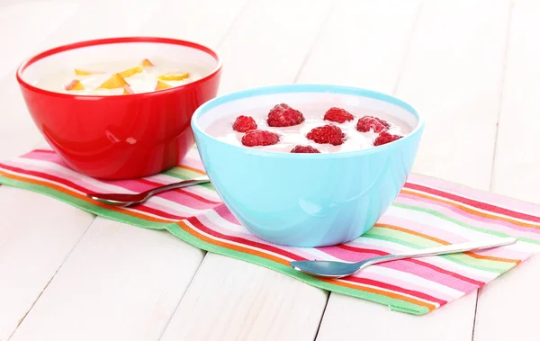 Йогурт с персиками и малиной в мисках на деревянном фоне — стоковое фото