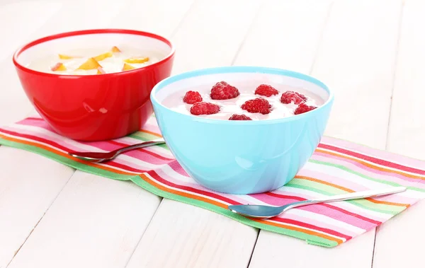 Yogur con melocotones y frambuesas en cuencos sobre fondo de madera —  Fotos de Stock