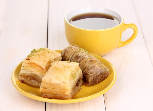 Zoete baklava op plaat met thee op houten achtergrond — Stockfoto