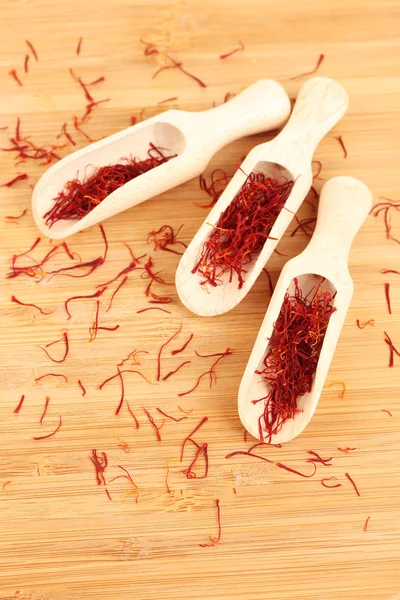 Stigmas of saffron in wooden spoons on wooden background close-up — Stock Photo, Image