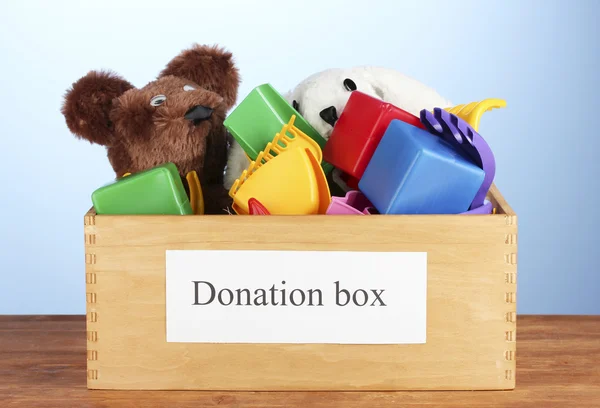 Donatie box met kinderen speelgoed op blauwe achtergrond close-up — Stockfoto