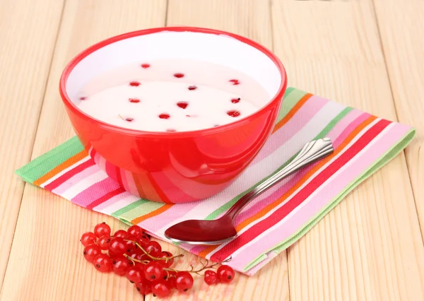 Jogurt s červený rybíz na dřevěný stůl — Stock fotografie