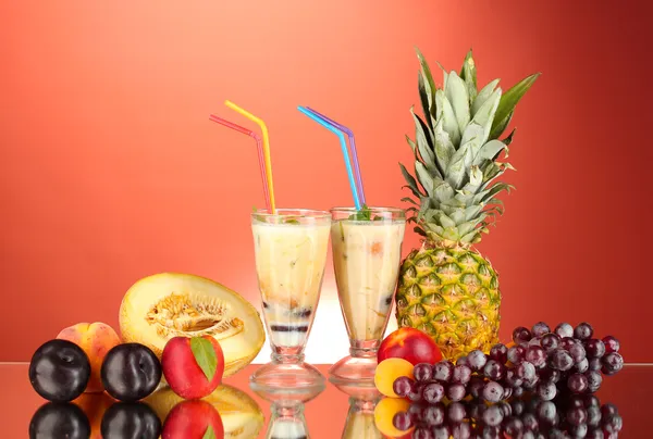 Mléčné koktejly s ovocem na červeném pozadí detail — Stockfoto