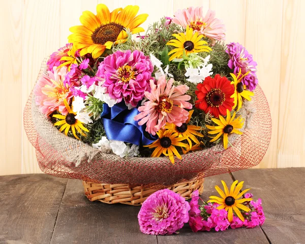 Mooi boeket van heldere bloemen in plundering op houten achtergrond — Stockfoto