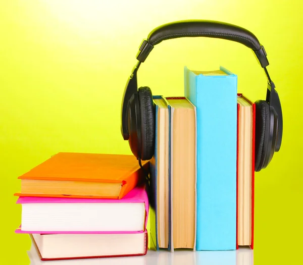 Auriculares en libros sobre fondo verde —  Fotos de Stock