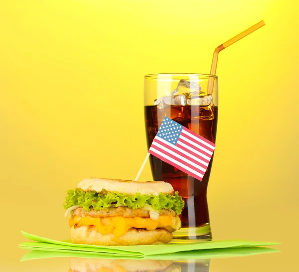 Sanduíche saboroso com bandeira americana e cola, sobre fundo amarelo — Fotografia de Stock