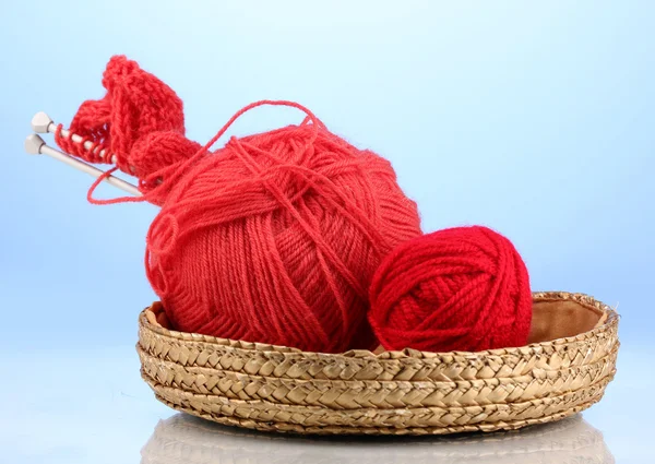 Red knittings yarns in basket on blue background — Stock Photo, Image