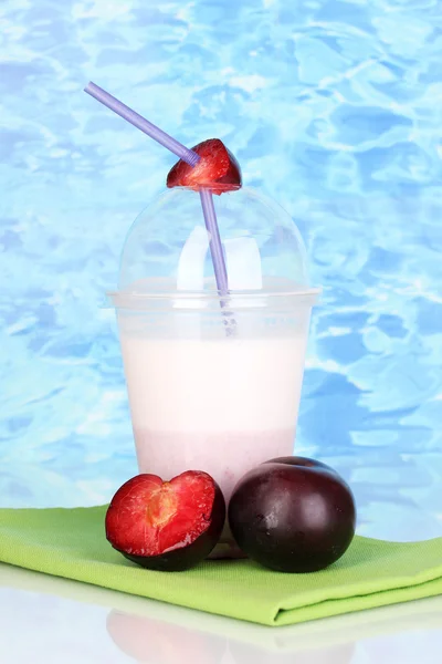 Deilig milkshake med frukt på bordet på blå havbakgrunn – stockfoto