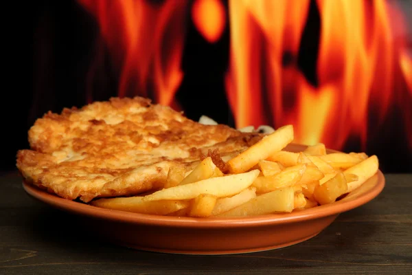 Stekt kyckling kotlett med pommes frites, på brand bakgrund — Stockfoto