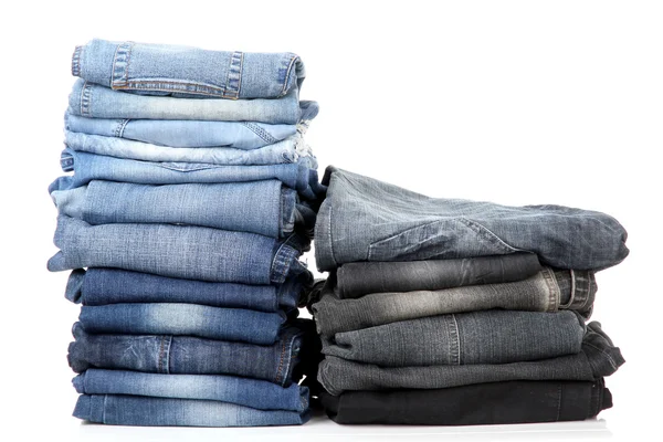 Veel jeans gestapeld in een geïsoleerd op witte palen — Stockfoto