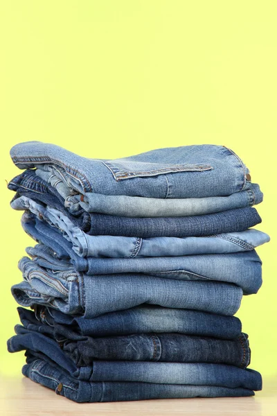 Veel jeans gestapeld in een stapel op groene achtergrond — Stockfoto