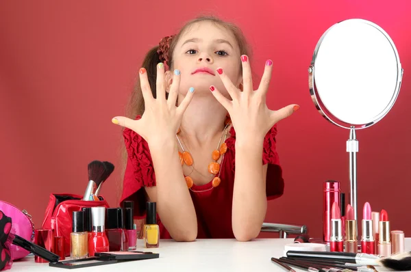 Маленькая девочка в мамином платье, пытается покрасить ногти — стоковое фото