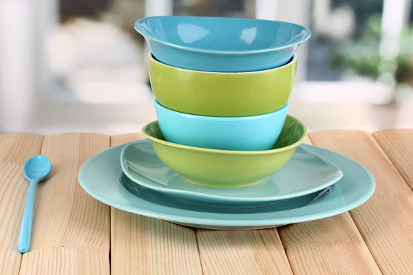 Голубая и зеленая посуда на деревянном столе на фоне окна — стоковое фото