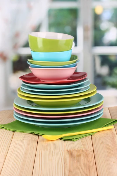 Colorful tableware on wooden table on window background — Stock Photo, Image