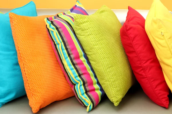Almohadas de colores en el sofá sobre fondo amarillo —  Fotos de Stock