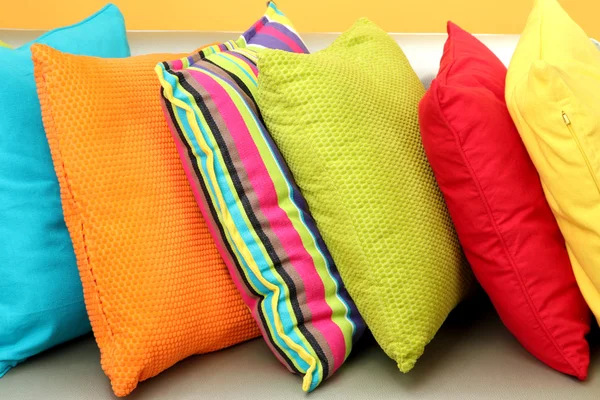 Colorful pillows on couch on yellow background — Stock Photo, Image