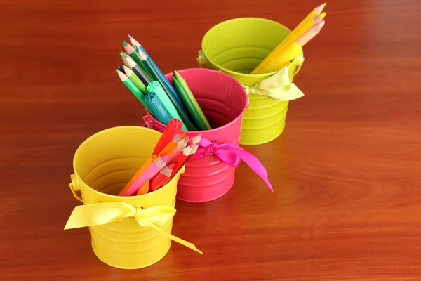 Lápices coloridos y plumas de fieltro en cubos de color de cerca en la mesa de madera — Foto de Stock