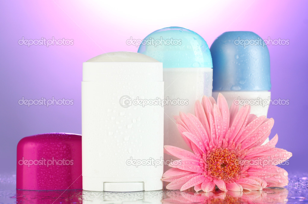 deodorant botttles with flower on purple background
