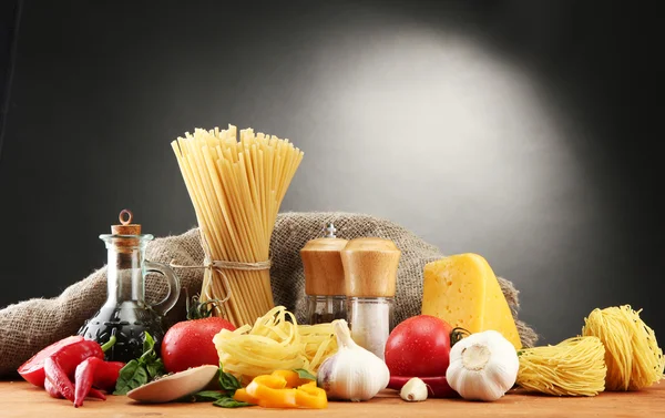 Makaron spaghetti, warzywa i przyprawy, na drewnianym stole, na szarym tle — Zdjęcie stockowe