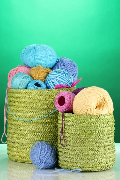 Colorful yarn for knitting in green basket on green background — Stock Photo, Image