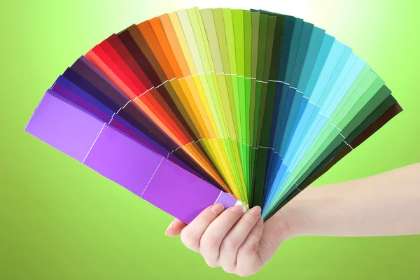 Hand holding bright palette of colors on green background — Stock Photo, Image