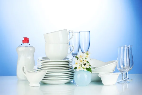 Platos limpios vacíos, vasos y tazas con líquido lavavajillas y flores en —  Fotos de Stock
