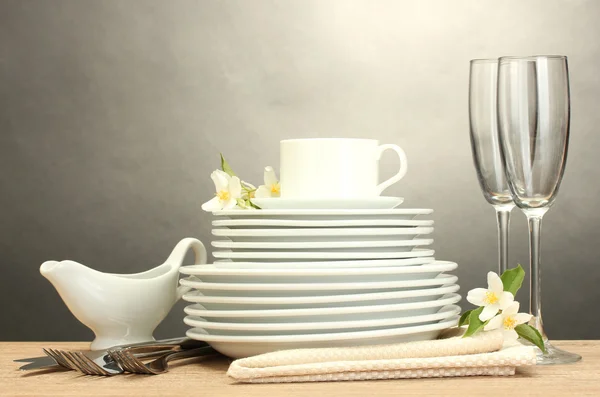 Lege schoon borden, glazen en cup op houten tafel op grijze achtergrond — Stockfoto