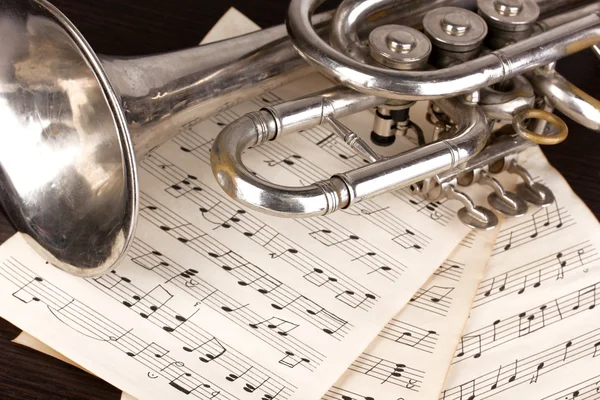 Musical notes and trumpet on wooden table — Stock Photo, Image