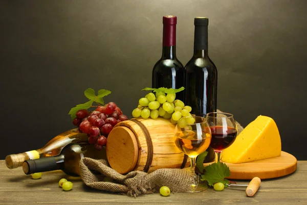 Fass, Flaschen und Gläser mit Wein, Käse und reifen Trauben auf Holztisch — Stockfoto