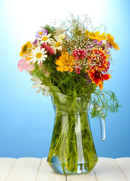 Beautiful bouquet of bright wildflowers in glass vase, on wooden table on — Stock Photo, Image