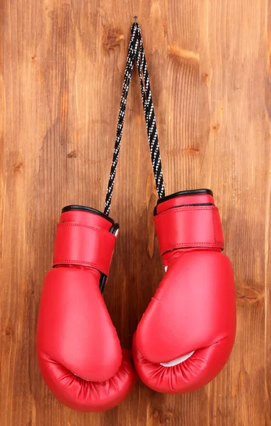 Guantes de boxeo rojos colgando sobre fondo de madera — Foto de Stock