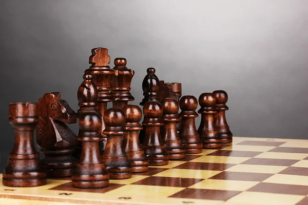 Schachbrett mit Schachfiguren auf grauem Hintergrund — Stockfoto