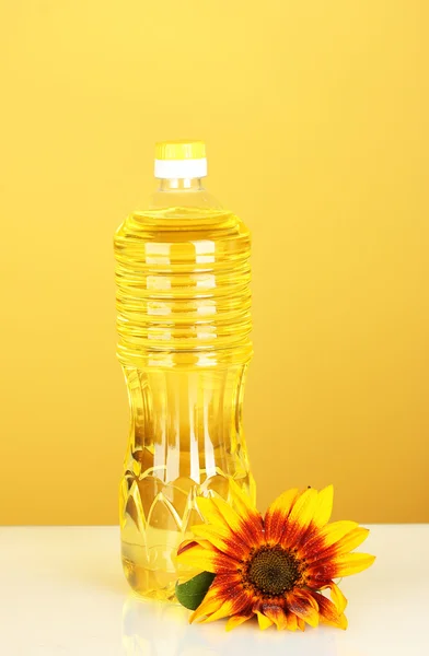 Подсолнечное масло в пластиковой бутылке на желтом фоне — стоковое фото