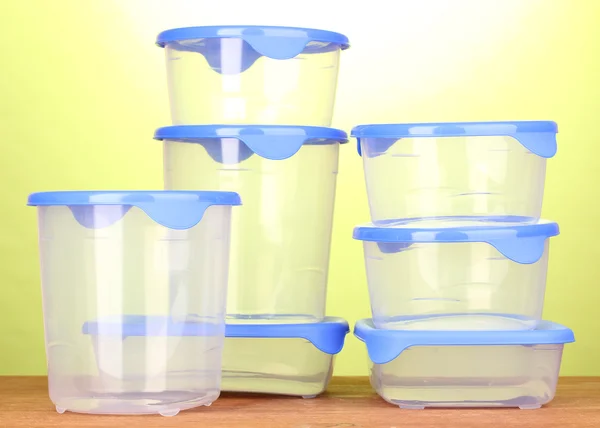 Plastic containers for food on wooden table on green background — Stock Photo, Image