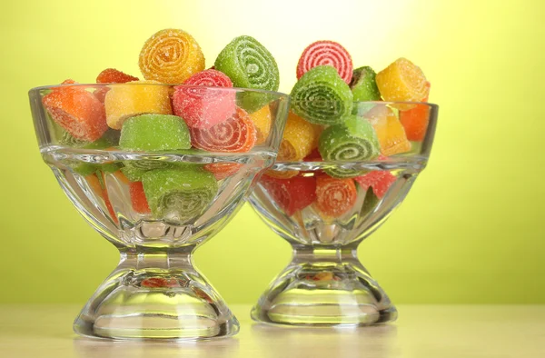 Colorful jelly candies in in glass bowls on green background — Stock Photo, Image