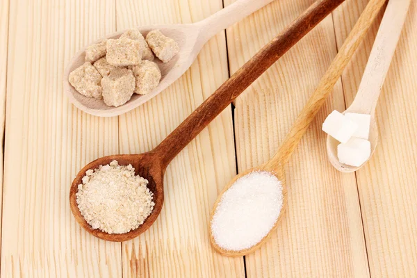 Белый и коричневый сахар в ложках на деревянном фоне — стоковое фото