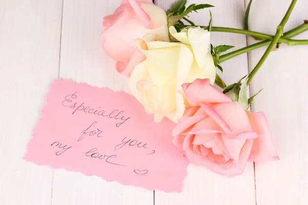 Tres rosas con tarjeta sobre fondo de madera —  Fotos de Stock