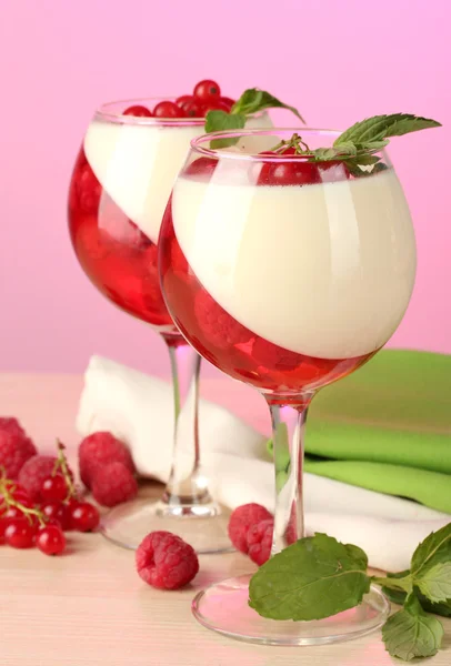 Gelatina di frutta con bacche in bicchieri su tavolo di legno su sfondo rosa — Foto Stock