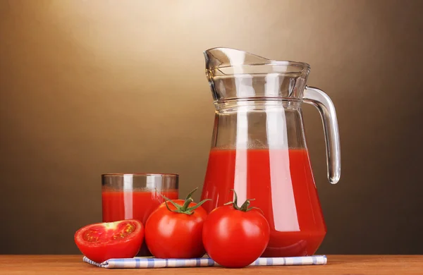 Tomatensaft in Krug und Glas auf Holztisch auf braunem Hintergrund — Stockfoto