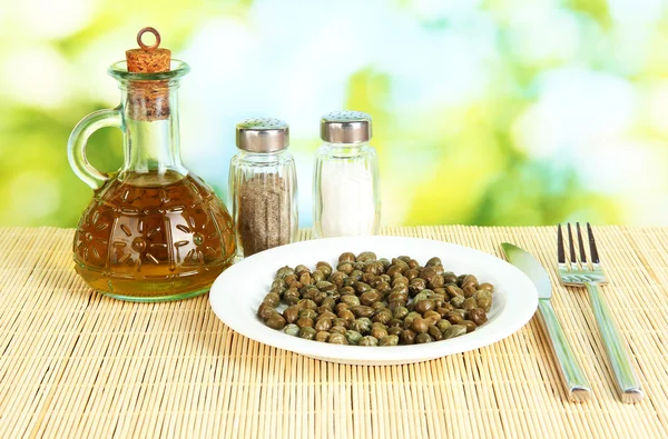 Capers in the plate on bright green background — Stock Photo, Image