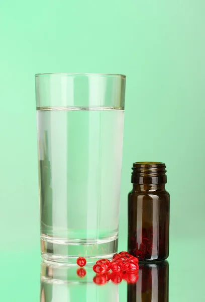 Un vaso de agua y pastillas sobre fondo verde de cerca — Foto de Stock