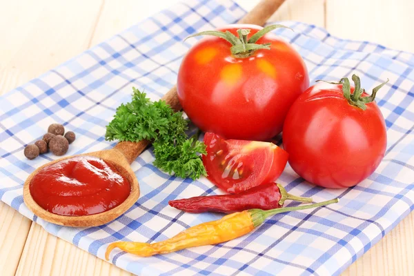 Ketchup en rijpe tomaten op houten tafel — Stockfoto