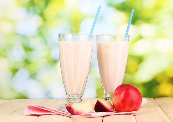 Персиковый молочный коктейль на деревянном столе на ярком фоне — стоковое фото
