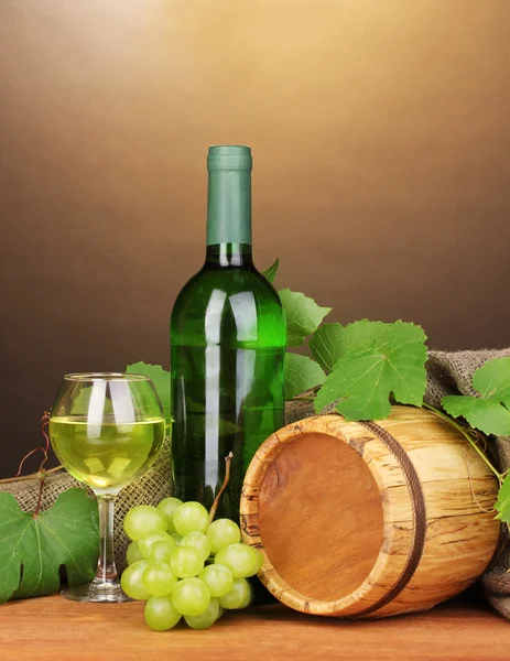 Бутылка отличного вина со стаканом и октавой на деревянном столе на коричневом фоне — стоковое фото
